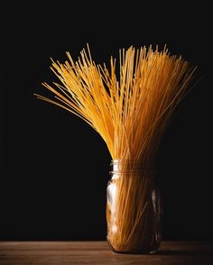 a vase filled with yellow straws on top of a wooden table