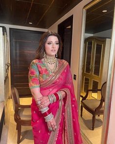 a woman in a pink sari and matching jewelry poses for the camera with her hand on her hip