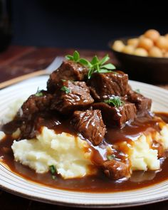 a white plate topped with meat and gravy covered in gravy on top of mashed potatoes