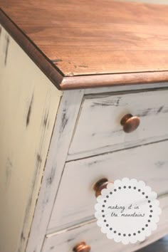 an old dresser is painted white and has brown knobs on the top drawer,