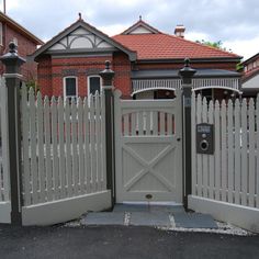 a white fence and gate in front of a house