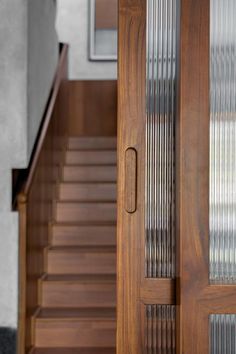 a wooden door with glass panels next to a set of stairs and handrails