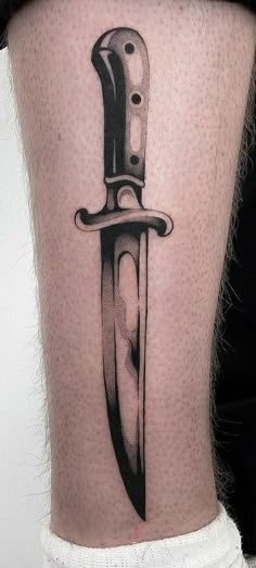 a knife tattoo on the leg of a woman's lower thigh, which is black and white