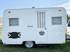 a white trailer parked on top of a lush green field