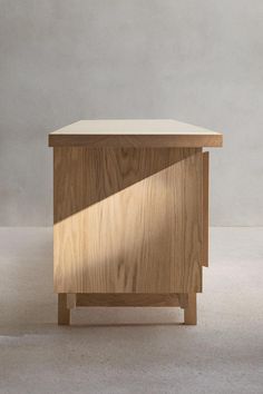 a small wooden cabinet sitting on top of a white floor next to a gray wall