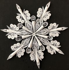 a snowflake made out of white paper on a black surface with buttons and spirals