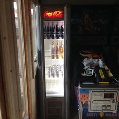 a vending machine sitting inside of a room next to a wall filled with soda bottles