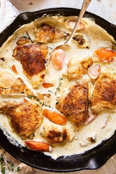 a skillet filled with chicken and carrots covered in gravy on top of a table