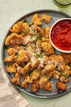 a plate filled with fried food next to a bowl of ketchup and sauce