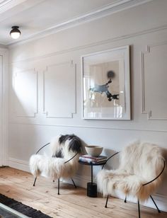 two white chairs sitting next to each other on top of a hard wood floor