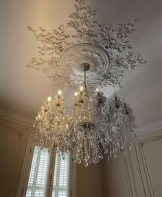 a chandelier hanging from the ceiling in a room with white walls and windows