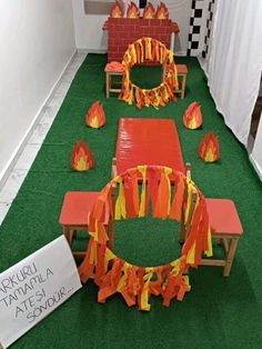 an arrangement of orange and yellow decorations on green carpeted flooring in front of white walls