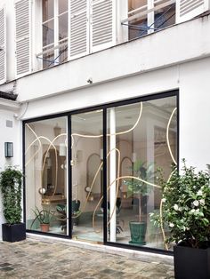 an outside view of a building with glass doors and potted plants on the sidewalk