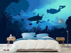 a bedroom scene with a bed, nightstands and wall mural depicting two people swimming in the ocean