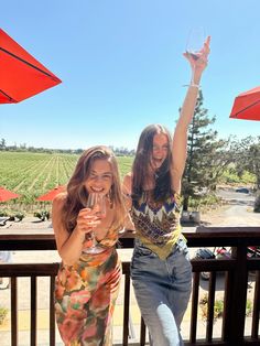 two women standing next to each other holding wine glasses