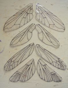 four metal wings are arranged in the shape of a christmas tree on a white wall