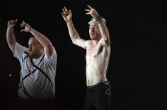 two men standing next to each other with their hands in the air and one man without his shirt on