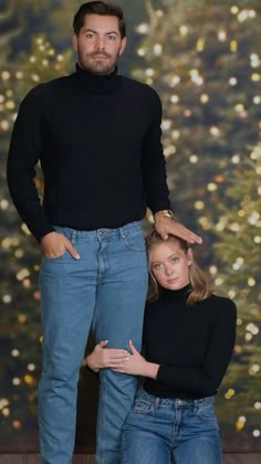 a man and woman standing next to each other in front of a wall with lights