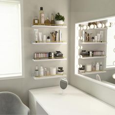 a white desk topped with a mirror and shelves filled with beauty products next to a window