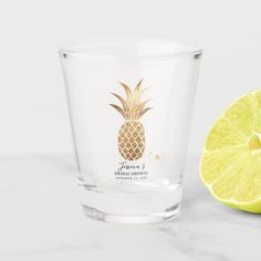 a shot glass with a pineapple logo on it next to a slice of lemon