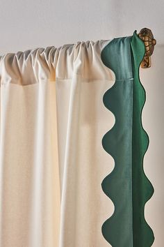 a curtain with green and white trim hanging on a rod