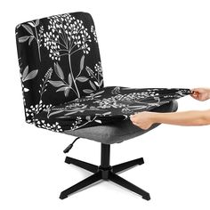 a person is sitting on a chair with a black and white flower pattern