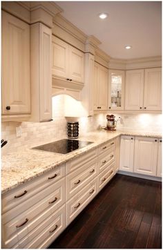 a kitchen with white cabinets and marble counter tops