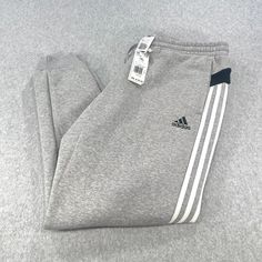 Elevate your activewear game with these stylish Adidas Multi Sport Jogger Pants in Men’s Size 2XL. Designed with a comfortable elastic waist and easy-care fabric, these pants are perfect for any season and any activity, whether you’re hitting the gym or going for a run outside. With water absorbent properties, these pants will keep you dry and comfortable during your workout. The gray color and white striped design, featuring the Adidas logo, make these pants a fashionable choice for any sports enthusiast. Featuring multiple pockets, these pants are both practical and stylish. Athleisure Jogging Bottoms With Three Stripes Branding, Athleisure Jogging Bottoms With Three Stripes, Athleisure Bottoms With Three Stripes For Jogging, Adidas Relaxed Fit Sweatpants With Three Stripes, Adidas Three Stripes Sweatpants For Jogging, Adidas Sweatpants With Three Stripes For Jogging, Relaxed Fit Three Stripes Sweatpants For Jogging, Adidas Sportswear Jogging Bottoms, Adidas Sportswear Bottoms For Jogging