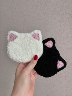 two crocheted cat ears are held up by a woman's hand