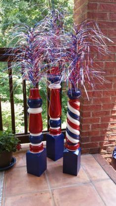 three tall red, white and blue vases with streamers in them on a patio