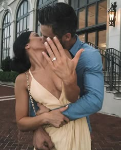 a man and woman kissing in front of a building with their hands on each other