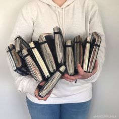 a woman is holding several stacks of records in her hands while wearing a hoodie