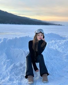 a woman sitting in the snow wearing ski goggles