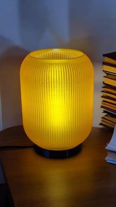 a yellow lamp sitting on top of a wooden table next to a stack of books