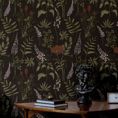 a table with a clock on top of it next to a wall covered in flowers