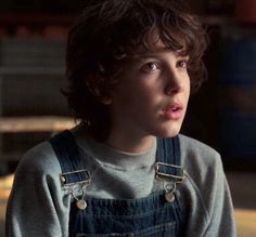 a young man in overalls is staring at the camera