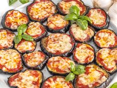 stuffed eggplant with cheese and spinach on a white plate next to garlic