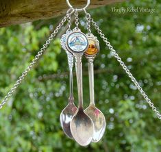 three spoons hanging from a chain with trees in the background