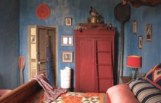 a living room with blue walls and pictures on the wall, including a red cabinet