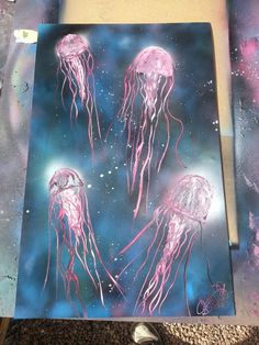 some pink jellyfish are floating in the water on a blue and purple painting board