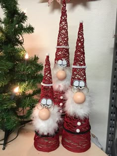 three red and white christmas trees sitting on top of a table next to a tree