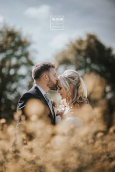 a bride and groom standing in tall grass