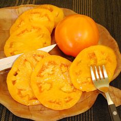 a plate with some tomatoes and a knife on top of it next to a fork