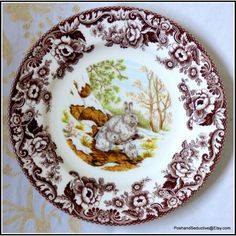 a plate with an image of two cats in the woods on it's side