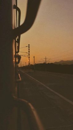 the sun is setting over an empty road with power lines in the distance and telephone poles on either side