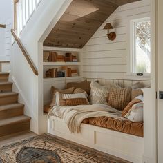 a room that has some pillows on the floor and stairs in it with bookshelves