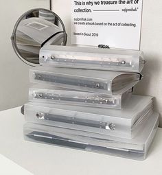 a stack of clear plastic boxes sitting on top of a white counter next to a mirror