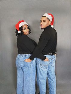 two people dressed in jeans and santa hats standing next to each other with their hands on their hipss