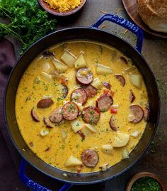 a pan filled with potatoes and sausages on top of a table next to bread