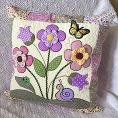 a close up of a pillow on a bed with flowers and a butterfly in it